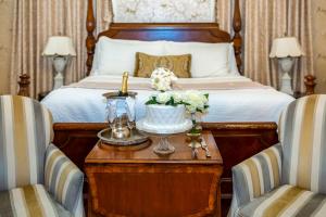 萨凡纳The Gastonian, Historic Inns of Savannah Collection的一间卧室配有一张床和一张桌子及一瓶香槟