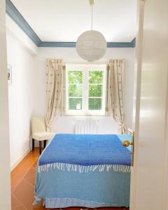 圣地亚哥-杜卡森Quinta das Tílias的一间卧室设有蓝色的床和窗户。