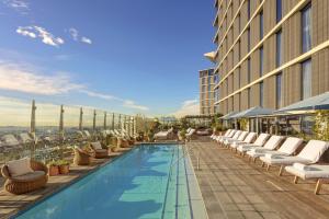 洛杉矶1 Hotel West Hollywood的酒店游泳池设有躺椅,酒店大楼