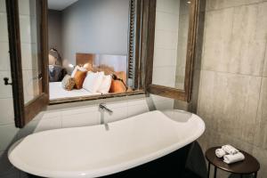 新普利茅斯国王和王后套房酒店的浴室设有白色水槽和镜子