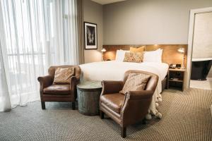 新普利茅斯国王和王后套房酒店的酒店客房,配有一张床和两把椅子
