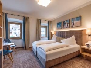 蒂罗尔-基希贝格Alpen Glück Hotel Unterm Rain garni的酒店客房配有一张床铺和一张桌子。