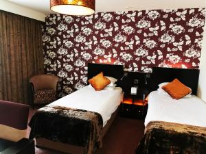 尼思风铃草酒店的一张位于酒店客房的床铺,配有花卉壁纸