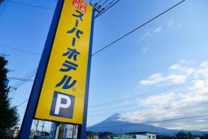 富士宫市Super Hotel Fujinomiya的 ⁇ 上的一个黄色标志,背景是山