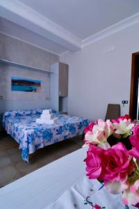 兰佩杜萨Bed and Breakfast Siciliamuri Lampedusa的一间房间,里面设有一张床和一张鲜花桌