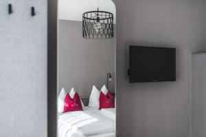 萨尔茨堡威瑟陶贝老城区酒店的一间卧室配有一张带红色枕头的床和一台电视。