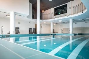 法莱拉Hotel Restaurant La Siala的一座铺有蓝色瓷砖地板的室内游泳池和一个大型游泳池