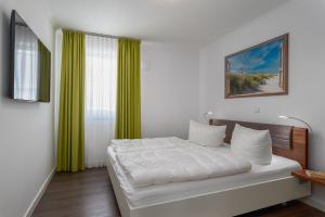 伯尔格伦德-雷特维施Ferienwohnungen Rosengarten的一间卧室配有白色床单和绿色窗帘