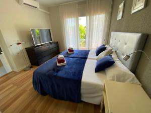 萨洛Victoria Beach Salou - Exclusive For Families的一间卧室配有一张带蓝色床单的大床和电视。