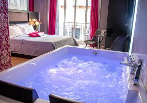 那不勒斯安吉尼奥Spa酒店的一张床铺的房间里设有一个大型蓝色浴缸