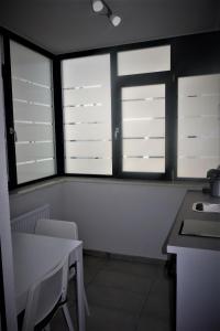 皮特什蒂Apartment Pitesti的厨房设有三扇窗户和一张桌子及椅子