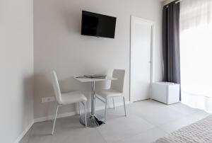 锡拉库扎PhotoRooms B&B的白色的客房配有桌子、两把椅子和电视。