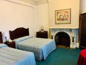 悉尼阿文莫尔公园精品酒店的一间卧室设有两张床和一个壁炉