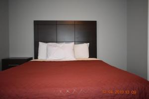 PetawawaTime Travellers Motel的一张带红色毯子和白色枕头的床