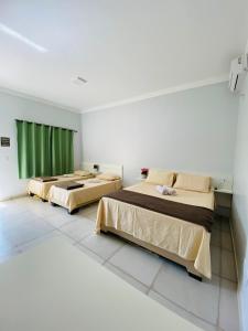 卡塔洛Hotel Pousada Marra的绿窗帘间内的两张床
