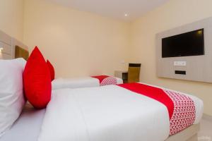 孟买Hotel Embassy Suites - Bandra Kurla Complex - BKC Mumbai的一间卧室配有两张带红色枕头的床和电视。