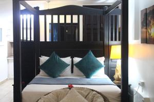 昂斯布瓦洛史戴夫娜公寓酒店的一间卧室配有带绿色枕头的黑色天蓬床