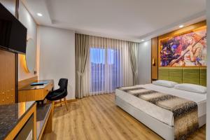 欧库卡拉Sealife Buket Resort & Beach Hotel - Ultra All Inclusive的酒店客房配有一张床、一张书桌和一台电视。