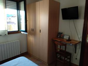 MendexaPension zelaigane的一间卧室配有一个橱柜和一张书桌及一台电视机