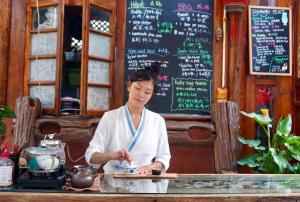 丽江Lijiang Jayden Lodge臣安山居民宿 - Namaste的坐在餐厅桌子上的女人