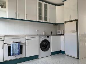 擞莫Duplex a 25 metros de la playa的厨房配有白色橱柜、洗衣机和烘干机