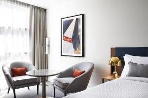 悉尼Crowne Plaza Sydney Darling Harbour, an IHG Hotel的酒店客房带一张床、一张桌子和椅子