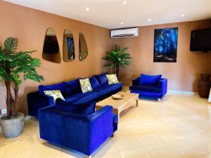 达喀尔Airport Hotel Casino du Cap-vert的客厅配有蓝色的沙发和电视