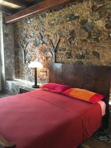 SantʼOnofrioB&B Le Casette的一间卧室配有一张红色的床和石墙
