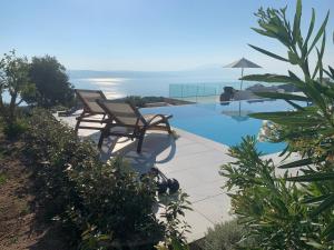 KechriaVilla Salina Luxury Pool Villa的一个带两把椅子的游泳池以及大海