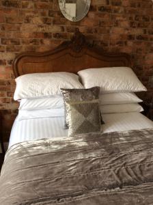 High EtherleyHolly Tree Cottage的砖墙旁的一张带白色床单和枕头的床