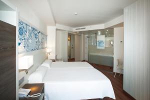 贝尼多姆贝尼多姆港口温泉酒店的一间带白色大床的卧室和一间浴室