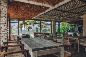 图卢姆Chiringuito Tulum的餐厅设有大桌子、椅子和窗户