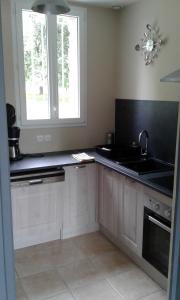 Aunay-sur-OdonLe Lutice的厨房配有白色橱柜、水槽和窗户。