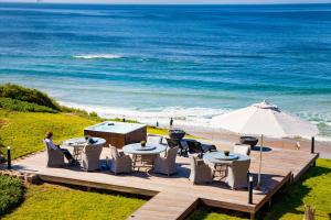 莫塞尔湾非洲海洋庄园酒店的一个带桌子和遮阳伞的甲板和大海