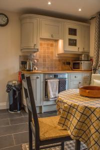 KirkmichaelReayrt Ny Marrey的厨房配有白色橱柜和带桌布的桌子