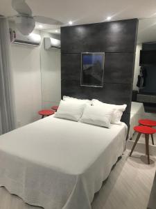 里约热内卢Ipanema Prudente Studio的卧室配有一张白色大床和两张红色桌子
