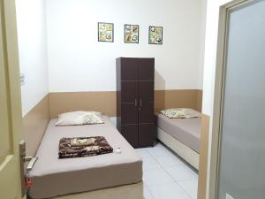 茂物Delta Inn Bogor Syariah for Indonesian Only的小房间设有两张床和橱柜