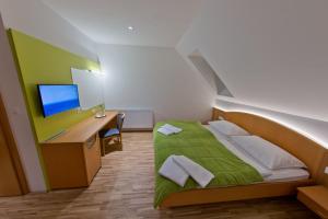 格拉茨附近卡尔斯多夫迈耶餐厅酒店的一间卧室配有一张带书桌和显示器的床
