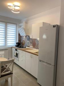 图尔恰Mia Apartament的白色的厨房配有冰箱和桌子