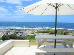 赫曼努斯Beachfront House - Hermanus Whale View的一张带雨伞的白色野餐桌和海洋