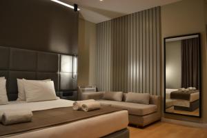 萨兰达ArtNest Luxury Hotel & Suites的一间卧室配有一张床、一张沙发和一面镜子