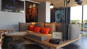 默伦默伦宜必思酒店的客厅配有带橙色枕头的沙发和桌子