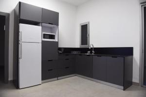 贝特谢安בית דירות - בית אורן的厨房配有黑色橱柜和白色冰箱。