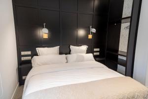 苏安塞斯La Playa Suites Suances的卧室配有一张带黑色床头板的大型白色床