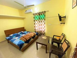 Surajpur JikklaTOURIST LODGE的卧室配有1张床、1张桌子和1把椅子