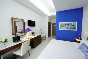 圣地亚哥米克诺斯酒店的一间卧室设有蓝色的墙壁、一张桌子和一张床