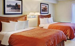 汤普森Thompson's Best Value Inn & Suites的酒店客房带两张带橙色床单的床