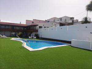 绍萨尔Alojamiento vacacional Linaje del Pago的一座带绿草的游泳池,位于大楼旁