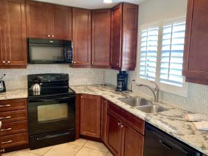 Point O'RocksIsland House Beach Resort 28的厨房配有木制橱柜、炉灶和水槽。