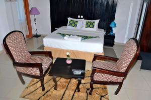 洛美Hotel BKBG的一间卧室配有一张床、两把椅子和一张桌子